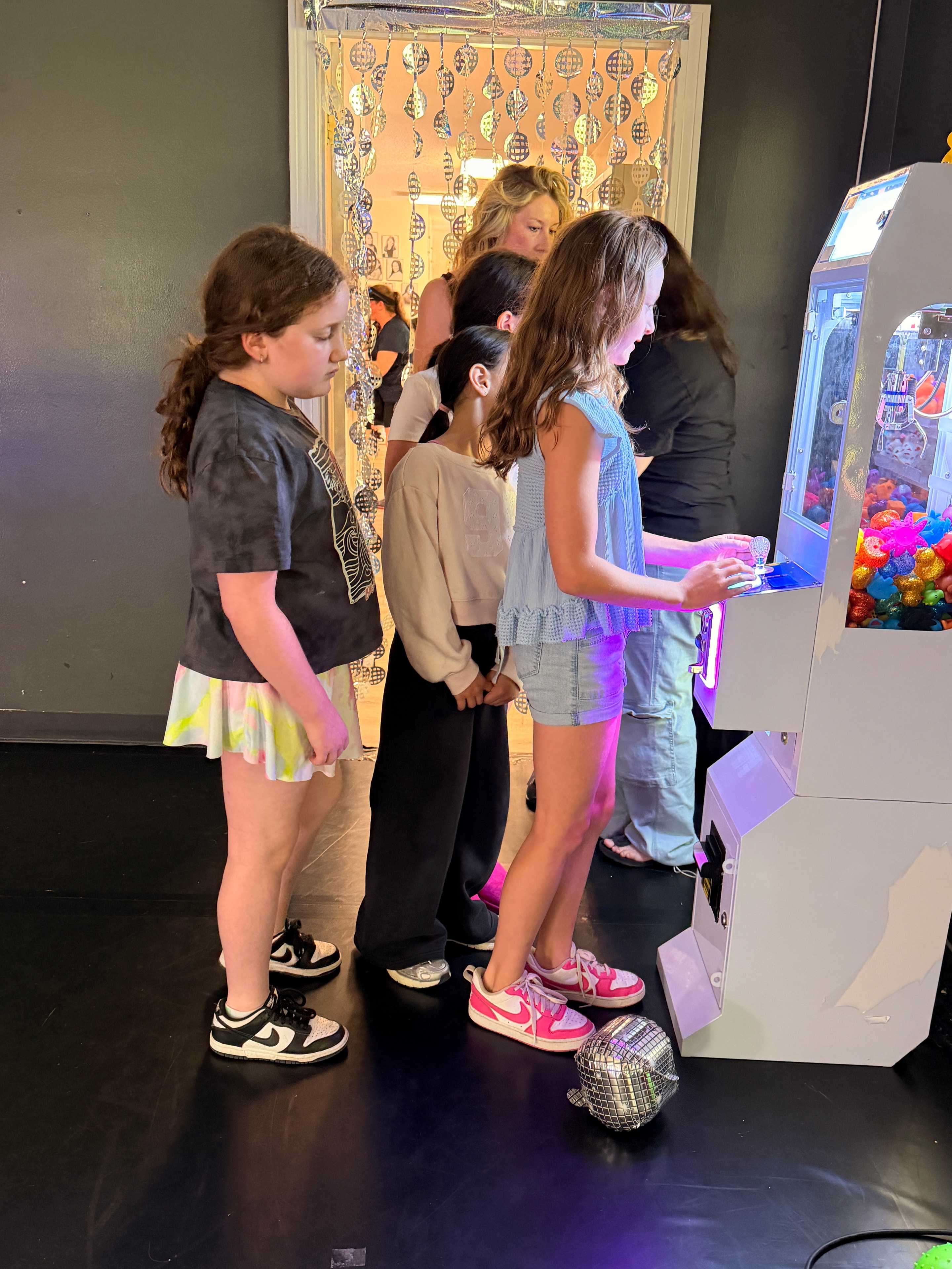 Kids gathered around the crane game at a party